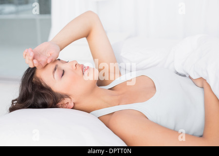Assonnato giovane donna che soffre di mal di testa con gli occhi chiusi nel letto Foto Stock
