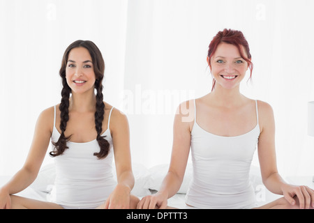 Due giovani donne in bianco canotte seduta sul letto Foto Stock