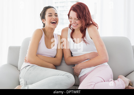 Due belle giovani amici di sesso femminile di ridere in salotto Foto Stock
