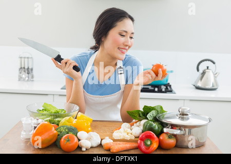 Donna sorridente tritare verdure in cucina Foto Stock