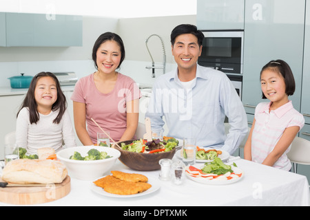 La famiglia felice di quattro godendo di pasto sano in cucina Foto Stock