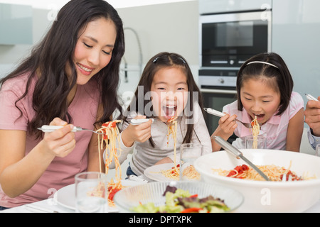 Donna con bambini godendo di spaghetti pranzo in cucina Foto Stock