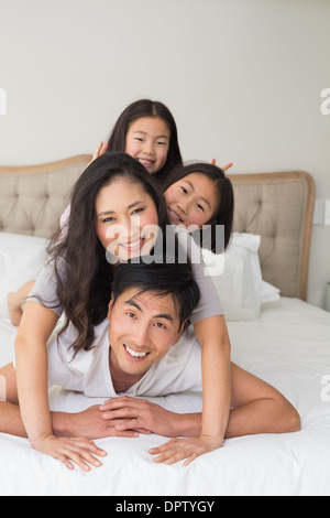 Allegro famiglia di quattro persone che giace al di sopra di ogni altro nel letto Foto Stock