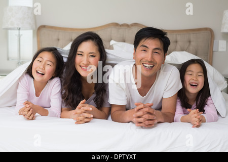 Ritratto di una famiglia allegra di quattro sdraiati a letto Foto Stock