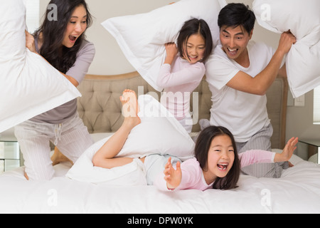 Famiglia di quattro avente lotta di cuscini sul letto Foto Stock