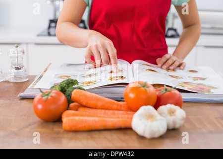 La sezione centrale di una donna con il libro di ricette e verdure Foto Stock