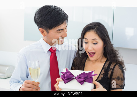 Scioccato donna apertura di una confezione regalo da uomo con champagne Foto Stock
