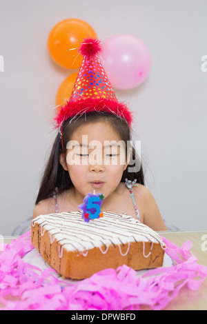 Carino bambina soffiando la sua torta di compleanno Foto Stock