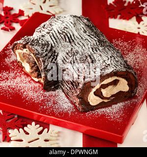 Yule log spugna di cioccolato crema vaniglia tradizionali di Natale targhetta rossa zucchero a velo spolvero fiocco di neve decorazione Foto Stock