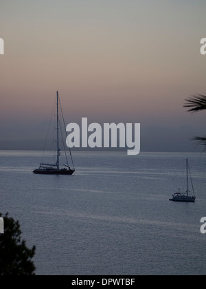 Silhouette di yachts come il sole sorge sulla baia di Palma Nova Maiorca Spagna Foto Stock