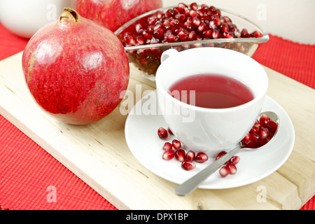 Prodotti freschi e salutari e Melograno antiossidante tè nella tazza bianca con fresca frutta Melograno e semi. Foto Stock