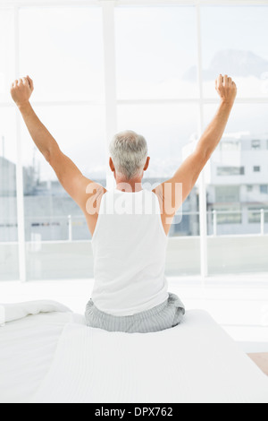 Vista posteriore di uomo maturo bracci di estensione a letto Foto Stock