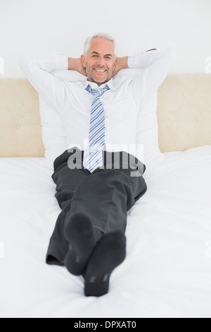 Rilassata imprenditore maturo seduto nel letto Foto Stock