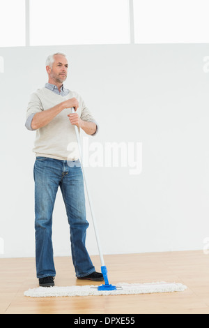 Lunghezza completa di un riflessivo uomo maturo in piedi con una scopa a frange Foto Stock