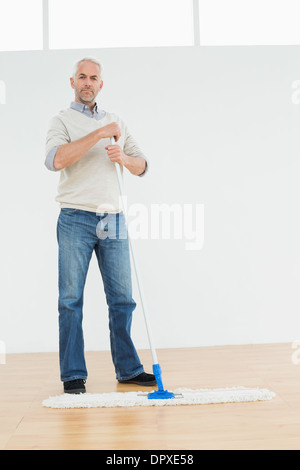 A piena lunghezza Ritratto di un uomo maturo in piedi con una scopa a frange Foto Stock
