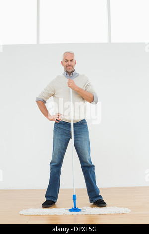 A piena lunghezza Ritratto di un uomo maturo in piedi con una scopa a frange Foto Stock