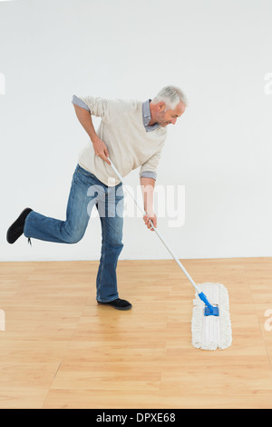 Lunghezza piena vista laterale di un uomo maturo con straccio il pavimento Foto Stock