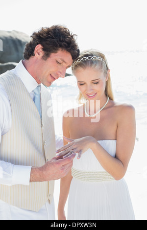 Uomo bello posizionando l'anello sul biondo sorridente brides dito Foto Stock