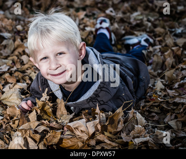 Ragazzo giocando con foglie Foto Stock