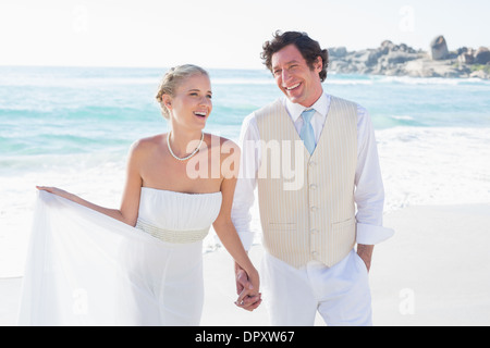 Sposi novelli camminando mano nella mano e ridere Foto Stock