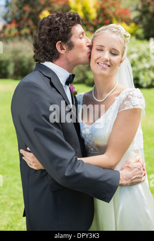 Lo sposo baciare la sua bella moglie di nuovo sulla guancia Foto Stock