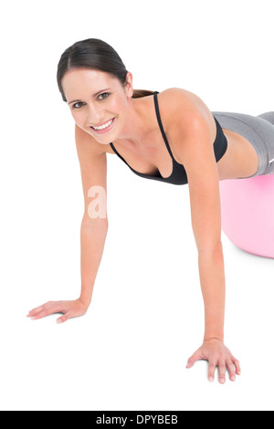 Montare la giovane donna facendo spingere ups sulla sfera di fitness Foto Stock