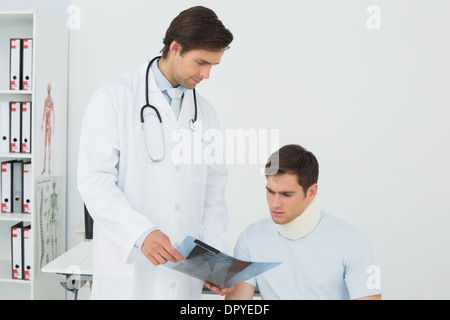 Medico spiegando la colonna vertebrale raggi x al paziente in ufficio Foto Stock