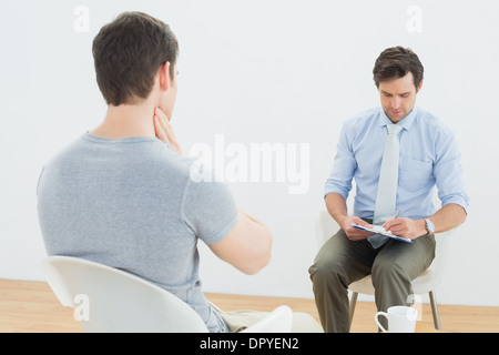 Ben vestito medico maschio in conversazione con il paziente Foto Stock