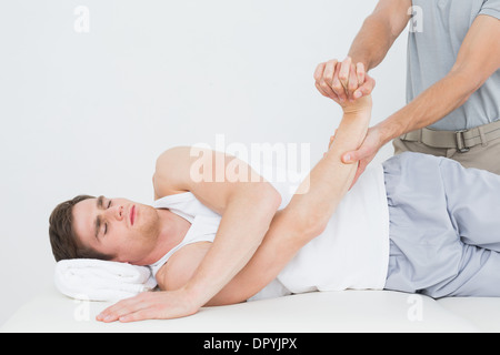 Fisioterapista maschio esaminando un giovane mans mano Foto Stock