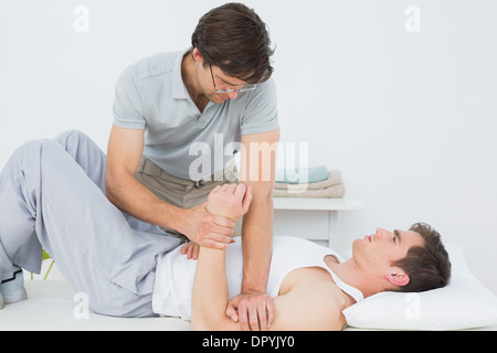 Fisioterapista maschio esaminando un giovane mans mano Foto Stock