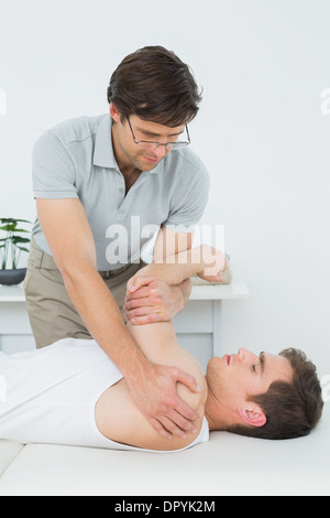 Fisioterapista maschio esaminando un giovane mans mano Foto Stock