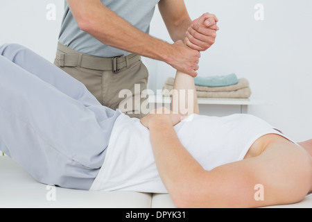 Fisioterapista maschio esaminando un giovane mans polso Foto Stock