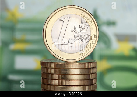 Un Euro moneta su una pila di monete in euro con una banconota da 100 Euro in background Foto Stock