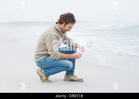 Vista laterale di un casual giovane uomo relax in spiaggia Foto Stock