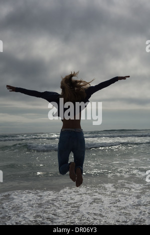 Lunghezza piena vista posteriore di una donna che si tuffa in spiaggia Foto Stock