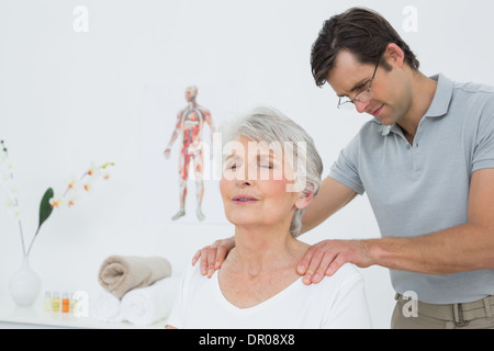 Fisioterapista maschio massaggiare una senior donna di spalle Foto Stock