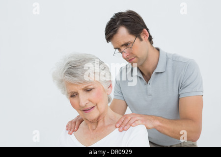 Fisioterapista maschio massaggiare una senior donna di spalle Foto Stock