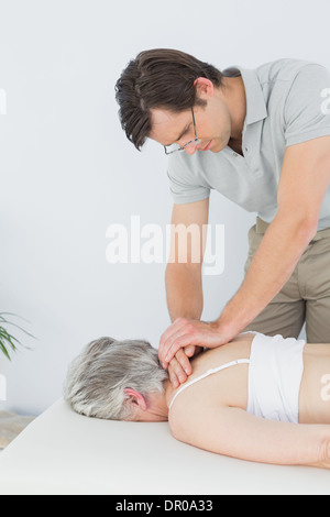 Fisioterapista maschio massaggiare una donna senior del back Foto Stock