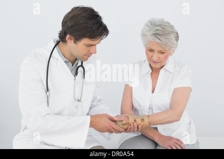 Fisioterapista maschio esaminando un senior donna di polso Foto Stock