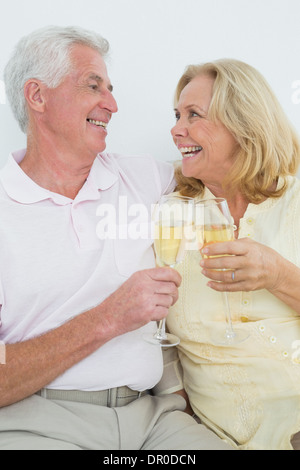 Coppia senior con champagne flutes a casa Foto Stock