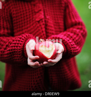 Bambino tenendo una mela rossa a forma di cuore Foto Stock