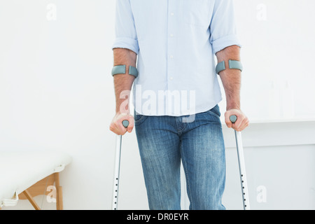 La sezione centrale di un uomo con le stampelle in ufficio medico Foto Stock