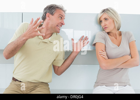 Donna con le braccia incrociate come uomo sostengono in cucina Foto Stock