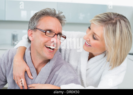 Donna che abbraccia un uomo da dietro in cucina Foto Stock