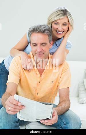 Coppia felice leggendo il giornale in soggiorno Foto Stock
