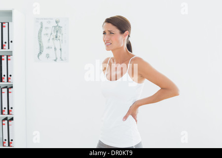 Vista laterale di una giovane e bella donna con dolore alla schiena Foto Stock