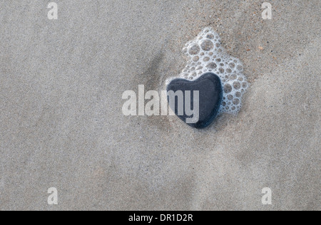 A forma di cuore sulla pietra di sabbia umida, Normandia, Francia Foto Stock