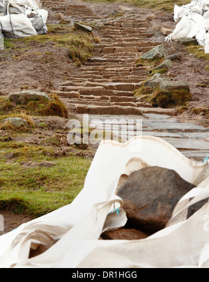 Riparazione di pietra erosa sentiero in corso sul Mam Tor, un popolare percorso pedonale vicino a Castleton, Peak District, Derbyshire, Regno Unito Foto Stock