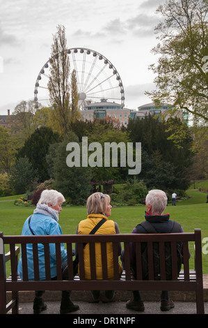 Vista posteriore di 3 grey-haired adulti seduti insieme su una panchina nel parco, chat, Relax & ammirando lo splendido paesaggio - Museo Giardini, York, Inghilterra, Regno Unito. Foto Stock