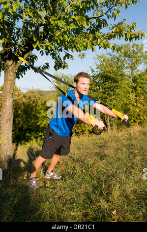 Un uomo utilizza gli anelli di sospensione Foto Stock